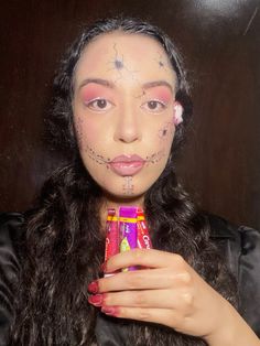 a woman with makeup on her face holding a candy bar