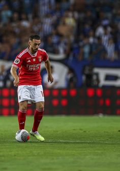 a soccer player in red and white is on the field with his foot on the ball