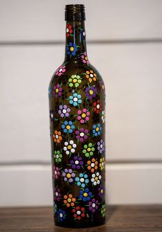 a bottle with multicolored dots on it sitting on a table next to a white wall