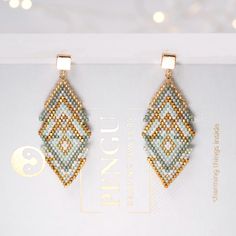 two pairs of beaded earrings sitting on top of a white box with lights in the background