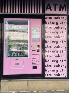 a pink atm machine sitting on the side of a building