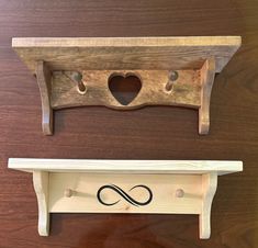 a wooden shelf with two hooks on it and a heart - shaped sign hanging from the top