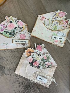 three envelopes with flowers are sitting on a table