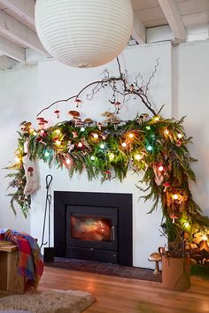 a fireplace decorated with christmas lights and greenery