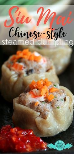 steamed dumplings with red sauce and carrots in the middle on a black plate