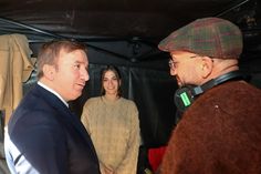 two men are talking to each other under a tent