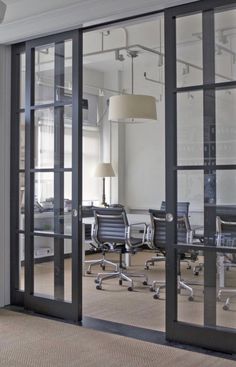 an office with glass walls and chairs in the middle is seen through large sliding doors