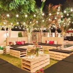 an outdoor seating area with wooden pallets and lights