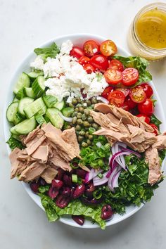 a salad with meat, tomatoes, cucumbers, olives and other vegetables