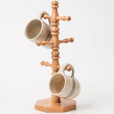 two mugs are hanging from a wooden rack on a white background and one is holding three cups