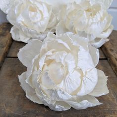 three white flowers sitting on top of a wooden table