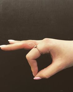 a woman's hand with a ring on her finger, against a black background