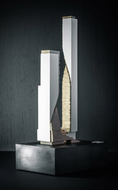 a tall white and gold sculpture sitting on top of a black table next to a wall