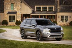 a grey suv is parked in front of a large house on a curvy road