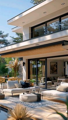 an outdoor living area with couches, tables and chairs in front of a house