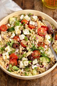 a close up of a bowl of food on a wooden table with a spoon in it