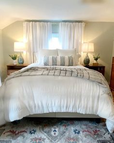 a white bed sitting in a bedroom next to two lamps on either side of it