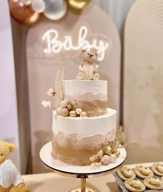 a baby shower cake with teddy bears and cookies on the table in front of it