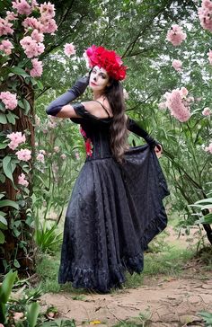 a woman with long hair wearing a black dress and red flower in her hair is posing for the camera