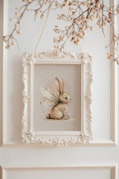 a white frame hanging on the wall with a bunny in it