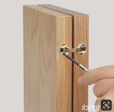 a person is holding a pen in front of a wooden box with the door open