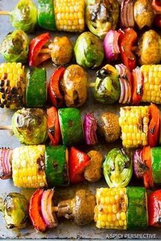 corn on the cob and vegetable skewers are ready to be grilled