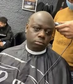 a man getting his hair cut in a barbershop with other people around him