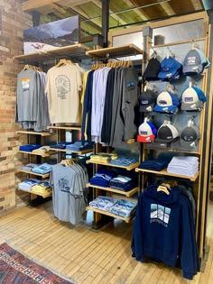 the inside of a clothing store with many items on shelves and hats hanging from racks