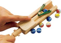 a hand is holding a wooden toy with balls