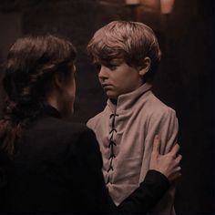 two people standing next to each other in front of a dark room with candles on the wall