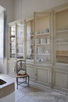 an old fashioned china cabinet with glass doors and shelves in the middle, filled with dishes