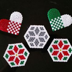 four beaded coasters in the shape of hearts and snowflakes on a black surface