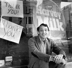 a man sitting in front of a store window with thank you signs on the windows