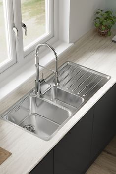 a stainless steel kitchen sink with two faucets on the side and a window behind it