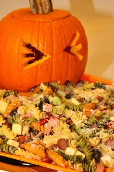 a pumpkin sitting on top of a tray filled with pasta