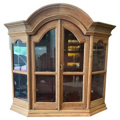 an old wooden corner cabinet with glass doors