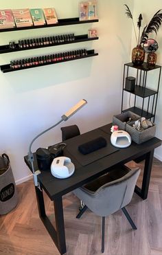 a table with two chairs and a lamp on it in front of shelves filled with nail polish bottles