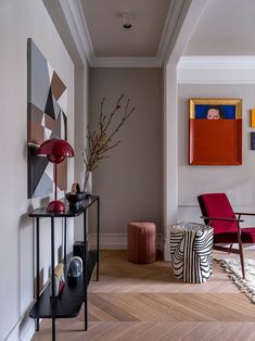 a living room filled with furniture and paintings on the wall next to a wooden floor