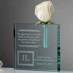 a glass vase with a white rose in it