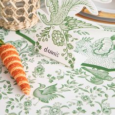 an orange carrot sitting on top of a table next to a basket and place card