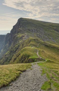 a path leading up the side of a mountain with grass growing on it's sides