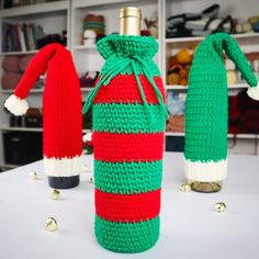 two crocheted wine bottles sitting on top of a table next to each other