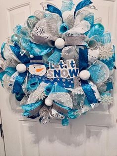 a blue and silver christmas wreath with snowman decorations on the front door for someone's house