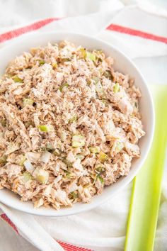 a white bowl filled with tuna salad next to celery