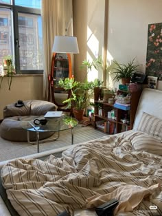 an unmade bed sitting in a bedroom next to a table with a lamp on it