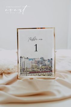 the table number is placed on top of an unmade bed in front of a cityscape