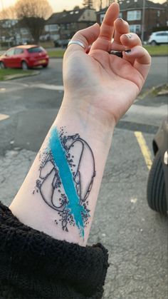 a woman's wrist with a blue ribbon on it and an arrow in the middle