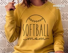 a woman wearing a baseball mom sweatshirt holding a pair of glasses in front of her face