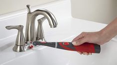 a person using a wrench to fix a faucet in a bathroom sink