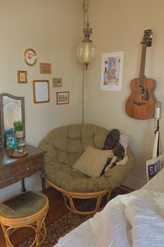 a bedroom with a guitar on the wall next to a chair and table in front of it